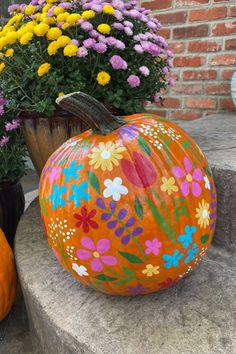 an orange painted pumpkin sitting on top of a cement slab next to potted plants