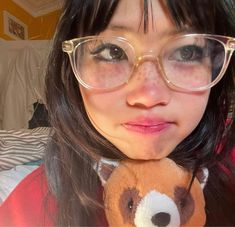 a woman wearing glasses and holding a teddy bear in her hand with the camera pointed at her face