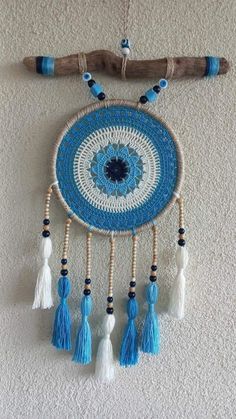 a blue and white dream catcher hanging on the wall next to a wooden stick with tassels