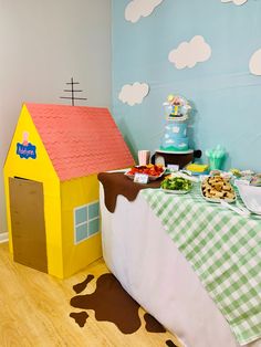 a table set up for a children's birthday party with a toy house on top