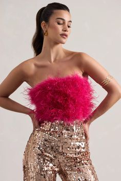 a woman wearing gold sequin pants and a pink feather bolery crop top