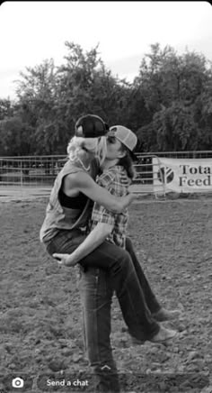 black and white photograph of two people hugging each other in front of a horse pen