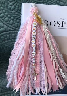 Accessorize your Bible with the Proverbs 31 Bible Tassel. Made with white lace, pink ribbons, gold and pink beads, and a gold rhinestone cross, this tassel adds a touch of elegance to your reading. Personalize it with your favorite Bible verse for a meaningful and beautiful addition to your Bible. Shabby Chic Bookmarks, Bedazzled Bible, Bible Tassel Ideas, Diy Bible Accessories, How To Make A Bible Tassel, Tassel Bookmark Diy, Bible Tassel Bookmark, Bookmark Tassel Diy, Bible Tassel Bookmark Diy