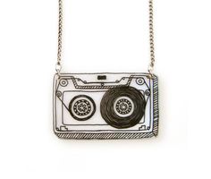 a necklace with a drawing of a cassette tape recorder on it's front and side