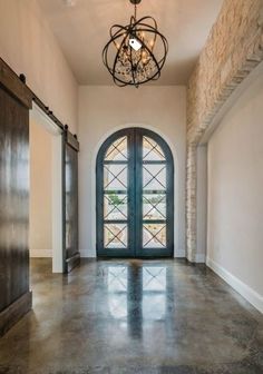 an empty hallway with two doors and a chandelier hanging from the ceiling