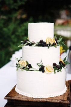 a white wedding cake with lemons and berries