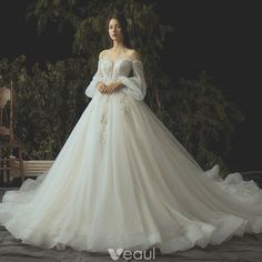 a woman in a white wedding dress standing on a wooden bench