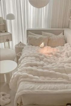 a bed with white sheets and pillows in a room next to a lamp on a table