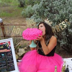 a woman in a pink dress sitting on a table with a menu and cupcake