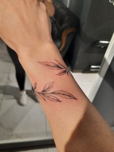 a person's arm with a small feather tattoo on it