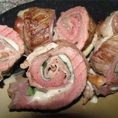 some meat rolls are sitting on a black plate and ready to be cut into small pieces