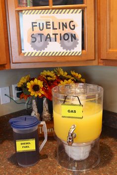 a yellow liquid in a container sitting on top of a kitchen counter next to a sign that says fueling station