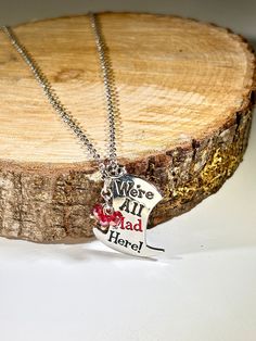 Tea Party Time! Alice in Wonderland Mad Hatter's Hat Pendant with "We're All Mad Here" engraved in it with letters coated with red and black enamel! Adorned by a cluster of AB red crystals and hung on a silver loop chain. This would make the perfect gift for tea lovers, Alice lovers, Mad Hatter lovers, etc.! There is a pair of matching earrings available, as shown in photos 9 & 10. To see the separate listing for the matching earrings, please click HERE:      - Mad Hatter We're All Mad Here top hat pendant measures         1 1/4" tall X 1 1/16" wide      - Alice in Wonderland Mad Hatter Necklace is 16 11/16" long      - Alice in Wonderland Mad Hatter necklace has a silver lobster         clasp To view more necklaces, click here: https://www.etsy.com/shop/AWeeBitOfLove?ref=hdr_shop_menu%C2% Handmade Themed Jewelry For Valentine's Day, Valentine's Day Themed Personalized Jewelry, Themed Adjustable Personalized Necklaces, Customized Adjustable Charm Necklaces For Valentine's Day, Time Alice In Wonderland, Alice In Wonderland Mad Hatter, Wonderland Mad Hatter, Mad Hatter Hat, Fantasy Necklace