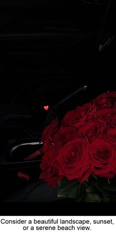 a bouquet of red roses sitting on top of a black table next to a cell phone