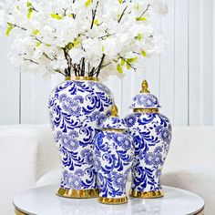 two blue and white vases with flowers in them on top of a coffee table