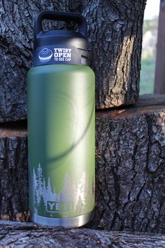 a green water bottle sitting next to a tree