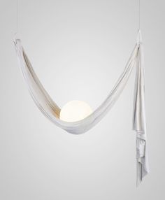 a white light hanging from the ceiling next to a bed with sheets draped over it