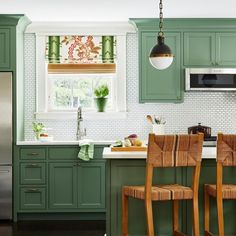 a kitchen with green cabinets and wooden chairs