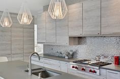 a modern kitchen with stainless steel counter tops and cabinets, along with pendant lights hanging from the ceiling