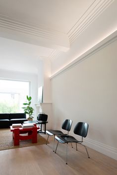 a living room filled with furniture next to a large window and wooden floored floors