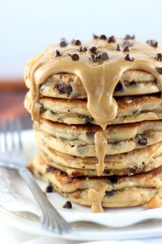 a stack of pancakes covered in chocolate chips and drizzled with peanut butter