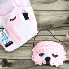 a pink and white mask sitting on top of a wooden floor next to a bag