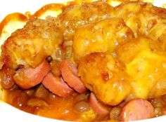 a close up of food on a plate with meat and beans in sauce, including potatoes