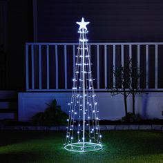 a lighted christmas tree in the grass at night with stars on it's top