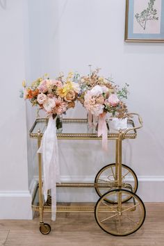 a gold bar cart with flowers on the top and ribbon tied around the handlebars