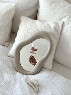 a white bed topped with pillows and a mirror on top of the headboard in front of it