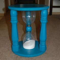 an hourglass sitting on the floor next to a table with a sand inside it