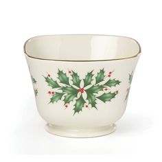 a white bowl with green and red holly decorations on the rim, sitting in front of a white background