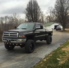 a large black truck parked on the side of a road in front of a house