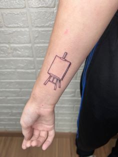 a person's arm with a small black and white easel tattoo on it