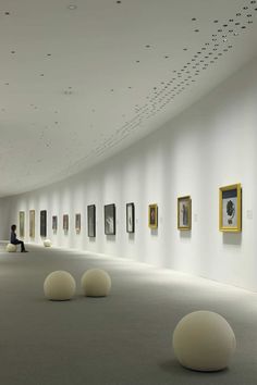 an art gallery filled with lots of white balls and paintings on the wall next to each other