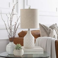 a living room with a couch, table and two vases on the coffee table