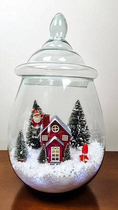 a snow globe with a red house and santa clause in it on a wooden table