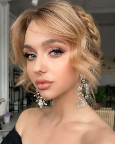 a woman with blonde hair wearing earrings and a black dress is looking at the camera