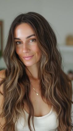 Woman with long wavy hair and a soft smile indoors. Lowlights Brunettes, Extensions With Highlights, Light Brunette Hair With Highlights, Long Brown Hair With Highlights, Brunette With Subtle Highlights, Low Maintenance Brunette Balayage Hair, Low Maintenance Brunette, Lived In Brunette