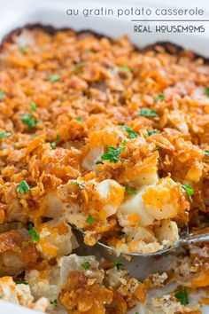 a casserole dish with potatoes and parsley in it, topped with a serving spoon