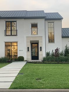 a white two story house with black trim and windows on the front door is shown