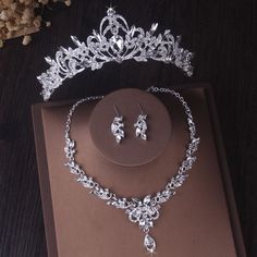 a tiara and earring set on display in a box with flowers behind it