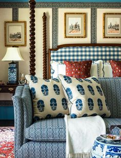 a blue and white couch sitting in a bedroom next to a table with a lamp on it