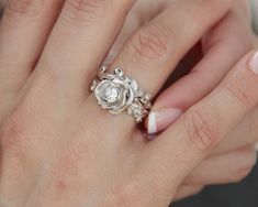 a close up of a person's hand with a ring on their finger and an engagement ring in the other hand