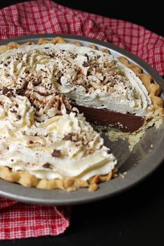 a chocolate pie with white frosting and sprinkles is on a plate