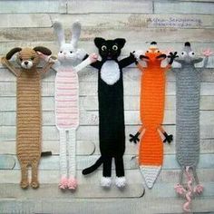 crocheted cats and mice are lined up on a wooden surface with their tails stretched out