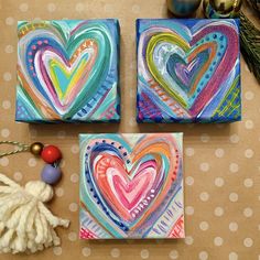 two colorful hearts are painted on canvases next to a tassel and other decorations