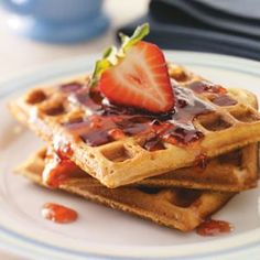 waffles topped with strawberries and syrup on a plate