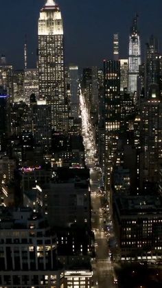 an aerial view of the city at night with skyscrapers and lights in the foreground