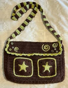 a crocheted brown and green purse with stars on the front, attached to a cord